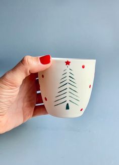 a woman's hand holding a coffee cup decorated with christmas trees