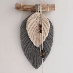 a wall hanging made out of yarn and wooden sticks with two leaves attached to it