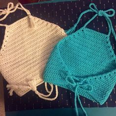 two crocheted swimsuits sitting on top of a blue mat next to each other