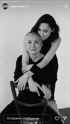 two women hugging each other while sitting on a chair