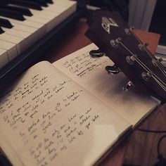 an open book sitting on top of a piano next to a keyboard with notes written in it