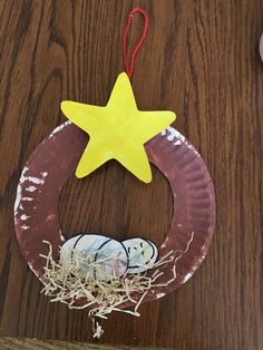 a paper plate wreath with a star hanging from it's side on a wooden table