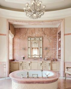 a fancy bathroom with pink marble and chandelier above the bathtub is pictured in this image