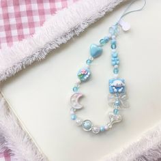 a blue and white beaded necklace sitting on top of a table next to a pillow