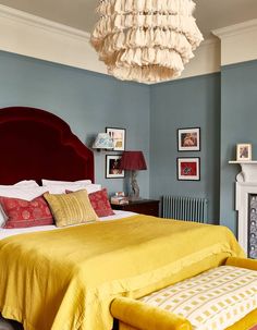 a bed room with a neatly made bed and a chandelier hanging from the ceiling