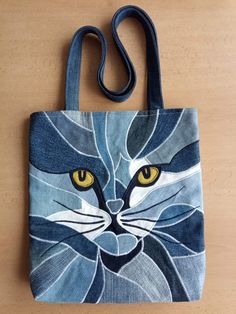 a blue and white cat bag with yellow eyes on the front, sitting on a wooden surface