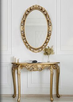 a gold table with a mirror and vase on it in front of a white wall