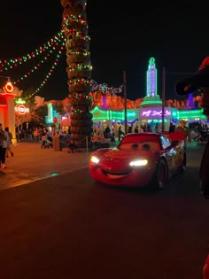 cars driving down the street at night with christmas lights and decorations on the buildings in the background