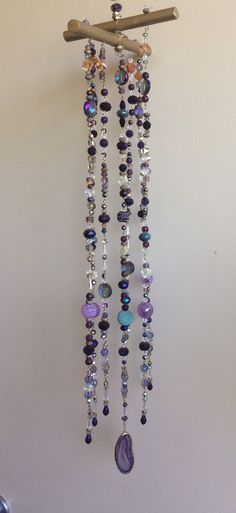 a wind chime hanging from the side of a wall with beads and stones on it