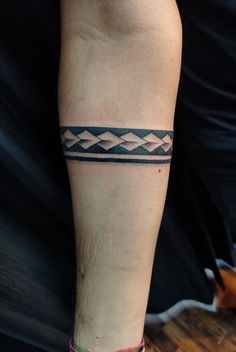 a man with a tattoo on his leg wearing a black and white bracelet that has an arrow in it