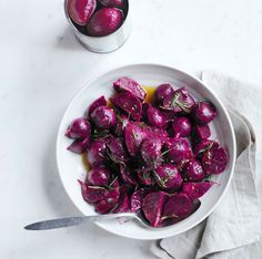 a white bowl filled with beets next to a glass of juice