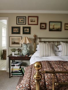 a bed sitting in a bedroom next to a lamp and pictures on the wall above it