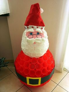 a santa clause is sitting on top of a large red object in the middle of a tiled floor