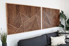 two wooden panels on the wall above a couch in a room with plants and pillows