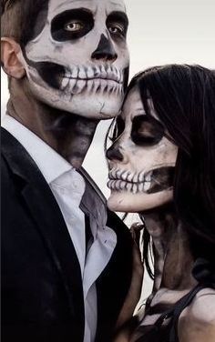 two people dressed up in skeleton makeup and black hair, one is kissing the other