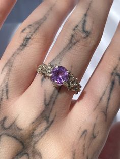 a woman's hand with a ring on it and a purple stone in the middle