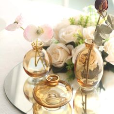 three glass vases with flowers in them on a table