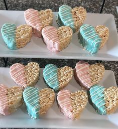 some heart shaped cookies are on two white platters with blue and pink icing