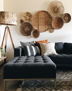 a living room with black couches and baskets on the wall