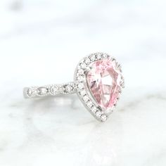 Elegant Vintage Inspired Pink Sapphire Ring ►Made of solid sterling silver with rhodium finish (925) ►Accented With Simulated Diamonds (CZ) ►Average band width: 2 mm Center Stone: Sapphire Color: Pink Shape: Teardrop Gem size: 7.0 x 10.0 mm Carat Weight: 2 ct. (approx.) Gemstone creation: 100% Natural Hardness: 9-9.5 (Mohs scale)- tests like a natural diamond ►Due to the gemstone nature, color of the gem may slightly vary. ✓ 100% Nickel-Free ✓ Hypoallergenic ✓ Comfort Fit ✓ Free Ring Box ✓ Free Silver Pear-shaped Halo Ring, Silver Teardrop Wedding Ring With Halo Setting, Classic Pink Cluster Ring For Anniversary, Teardrop Halo Setting Promise Ring, Classic Stackable Wedding Rings With Accent Stones, White Gold Teardrop Jewelry For Proposal, Classic Halo Design Jewelry For Proposal, Sterling Silver Pear-shaped Wedding Rings, Sterling Silver Pear-shaped Ring With Halo Setting