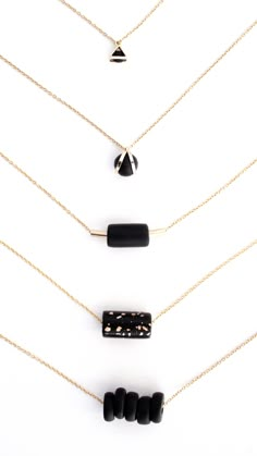 five black and gold necklaces on a white background