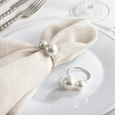 two white pearls are sitting on top of a napkin next to a fork and knife