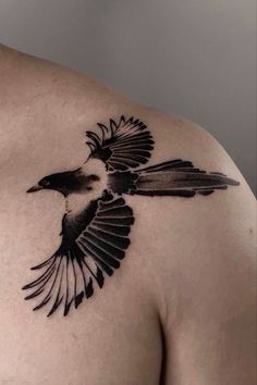 a black bird tattoo on the back of a man's shoulder