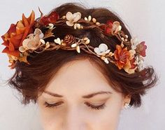 a woman wearing a flower crown with leaves on her head and hair comb in front of her face