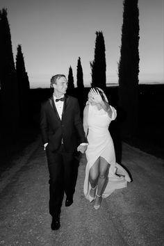 a man in a tuxedo walking next to a woman in a white dress