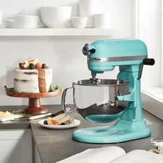 a blue mixer sitting on top of a kitchen counter next to a plate with food