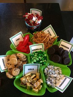 a table topped with green plates filled with candy and candies next to other snacks