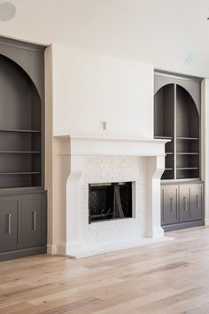 an empty living room with built - in bookcases and a fire place on the far wall