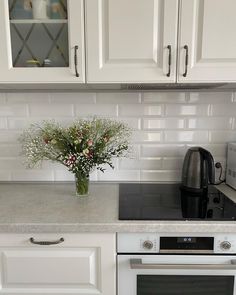 a vase with flowers sitting on top of a kitchen counter next to an oven and microwave