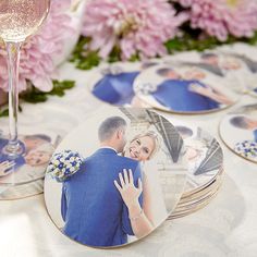 a table topped with plates covered in photos and wine glasses filled with pink flowers next to each other