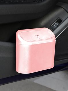 a pink box sitting on the side of a car door next to a steering wheel