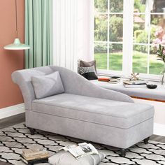 a white chaise lounge chair sitting on top of a rug in front of a window