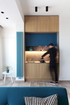 a person standing in front of a kitchen with blue cupboards and counter tops on the wall