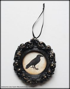 a black bird sitting on top of a wooden frame hanging from a string attached to a wall