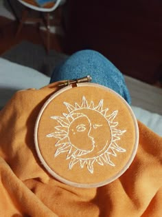 a hand embroidered sun and moon on an orange shirt