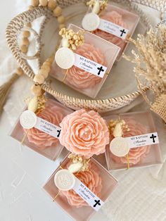 four small pink flowers in clear boxes on a white tablecloth with beads and gold accents