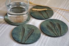 three coasters with wheat on them next to a glass of water