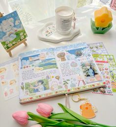 an open planner book sitting on top of a table next to tulips and flowers