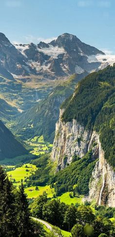 the mountains are covered in green grass and trees