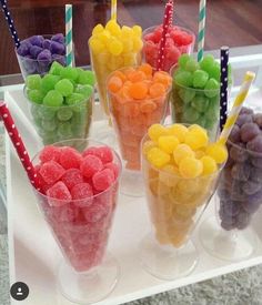 there are many different colored candies in cups on the table with striped straws