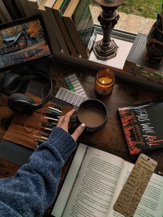 a person sitting at a table with books and headphones on it, next to an open book