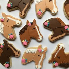 decorated cookies in the shape of horses with pink and brown icing on them, sitting next to each other