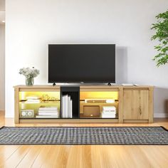 a living room with a large television on top of a wooden entertainment center next to a potted plant