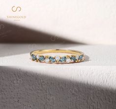 a yellow gold ring with blue and white stones on it's sides, sitting on a surface