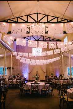 a banquet hall with tables and chairs covered in white tablecloths, lights and chandeliers hanging from the ceiling