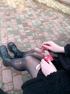 a woman is sitting on the ground with her legs crossed and holding a cell phone